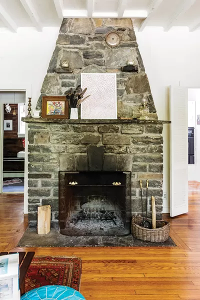 The massive stone fireplace features art by Josef Presser and Tanya Minhas, along with a bouquet of feathers gathered walking the property. - PHOTO: WINONA BARTON-BALLENTINE
