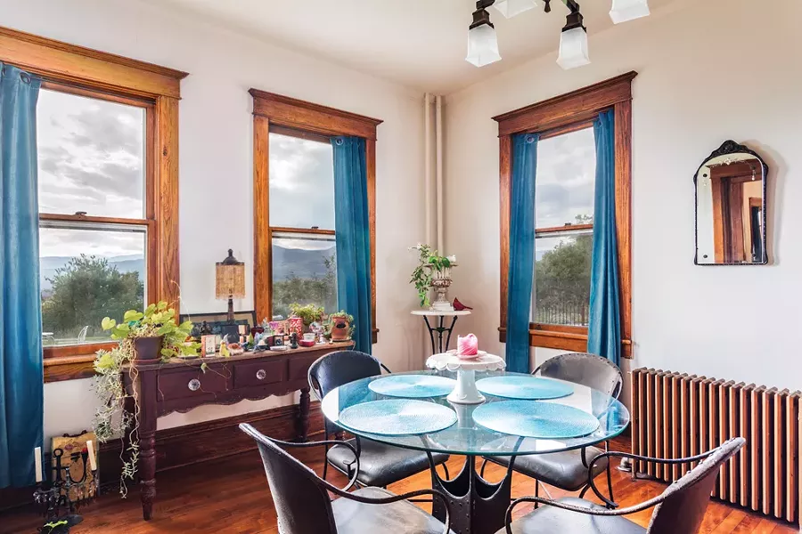 The first-floor dining room features an original cast iron radiator and updated light - fixtures. Raimondo bought the medieval style iron and glass table from Pier 1 and the French Provincial style sideboard from an antiques store in Chelsea. - PHOTO BY WINONA BARTON-BALLENTINE