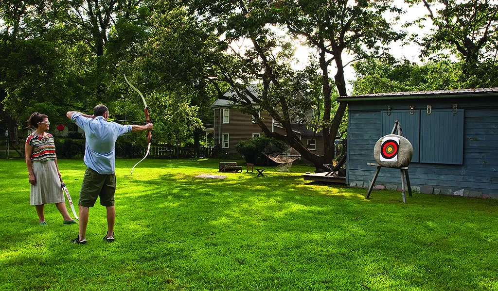 Christina Osburn and Paul O'Connor practicing archery in their backyard. - DEBORAH DEGRAFFENREID