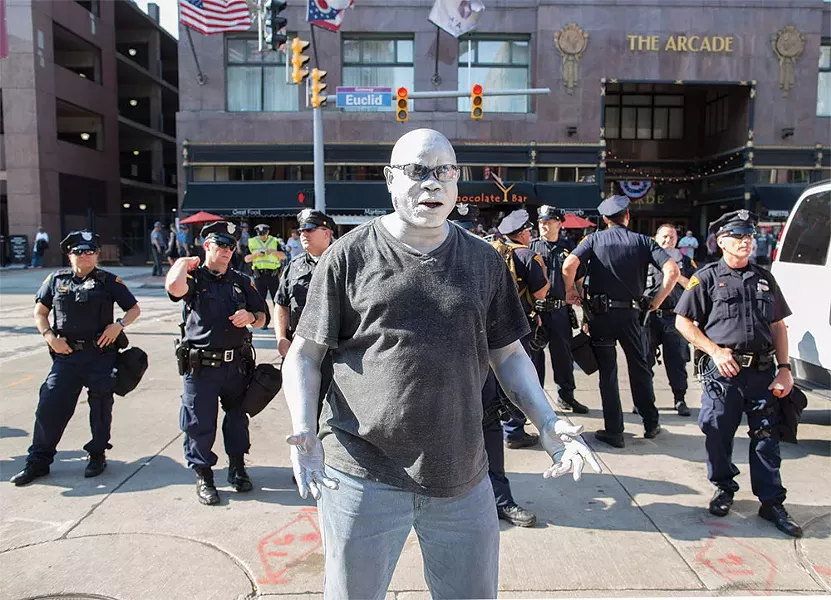 An Afro-American street performer in white face was amazed by a police presence that outnumbered demonstrators four to one. - FRANK SPINELLI