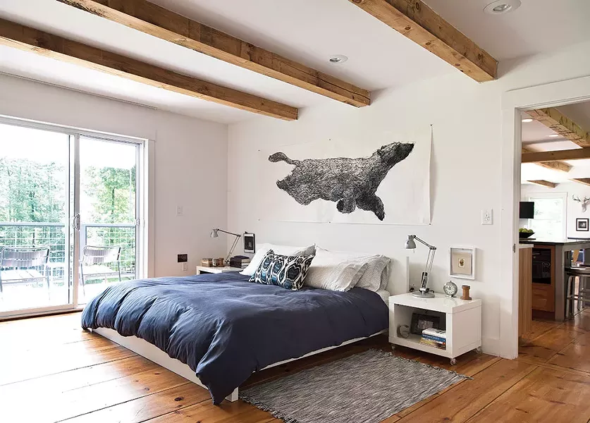 The couple’s bedroom overlooks the back deck and is decorated with pieces inspired by their wooded surroundings. The artwork above the bed, Ursa Major Lost At Sea by Aliene De Souza Howell, was purchased from One Mile Gallery in Kingston. - DEBORAH DEGRAFFENREID