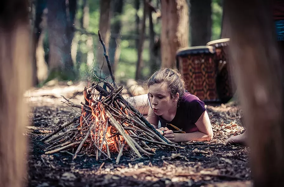 Student tending a fire at a Wild Earth program.