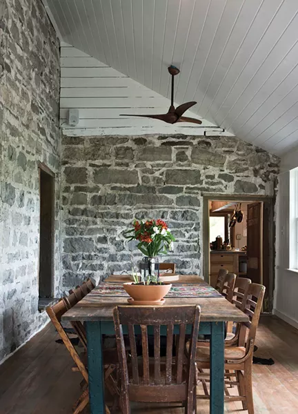 The three-season porch required extensive renovation. Once a covered porch, Zeller refinished the floor and walls, then installed new windows and insulated the ceiling. Now a dining area, it offers extensive views of the pool while retaining much of the stone house’s antique charm. - DEBORAH DEGRAFFENREID