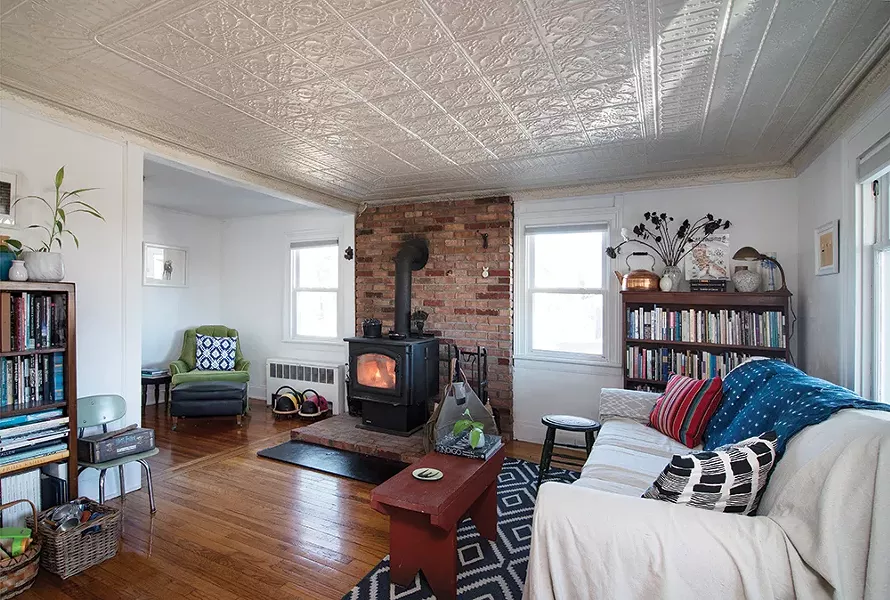 The couple added a wood stove to the front sitting room. The space is decorated with furniture pieces they’ve collected over the years, as well as pillows and throws handcrafted from natural fibers and hand dyed.