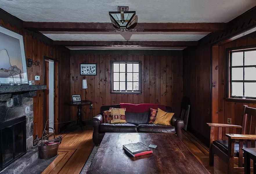 Stewart has filled the wood paneled den - with art and mementos from her parents and - grandparents. The paned leaded glass window - and Art Deco chandelier are original to the home. “This really does remind you of an old library,” she says. “It’s been nice to introduce things from my family. It gives the space a very warm feeling.” - PHOTO: DEBORAH DEGRAFFENREID