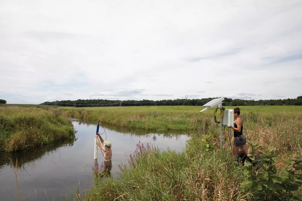 Matt Sheffer, managing director of Hudson Carbon, and former lab manager Lily Timpane install a water quality sensor in Old Mud Creek, a stream flowing through the farm. - MARTIN ADOLFSSON