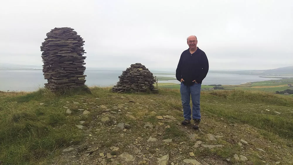 Laird Scranton with cairns atop Cuween Hill in the Orkney Islands off Scotland.