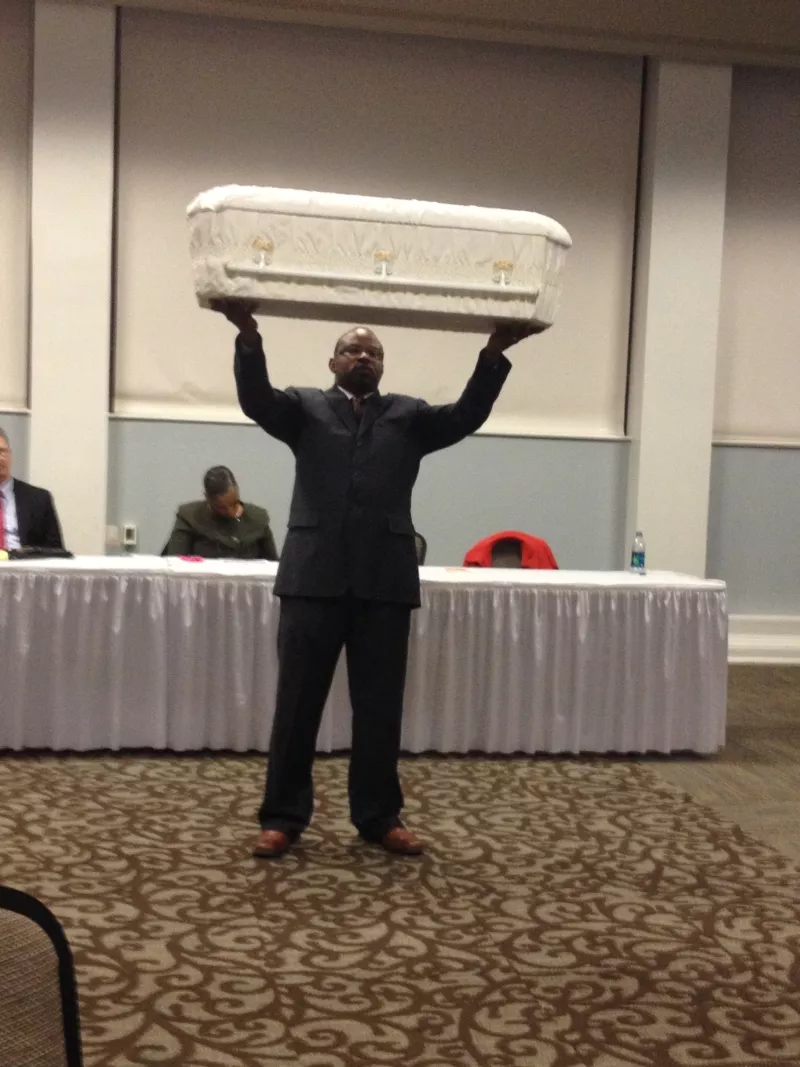 City Council candidate Detric Leggett held up a baby’s coffin as a silent protest of the Mayor’s record on crime. - JIM MOREKIS
