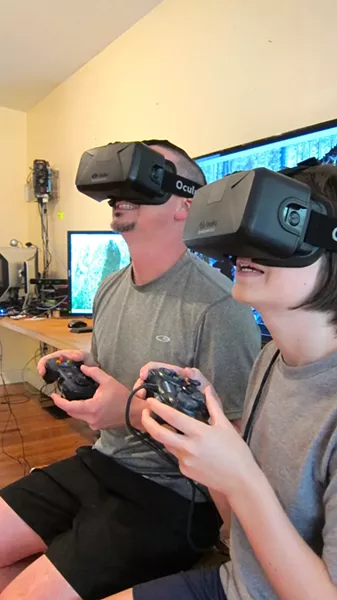 Roberson in his studio with son Clay using Oculus Rift virtual reality technology (custom computer on wall behind)