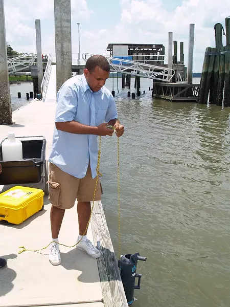 Skidaway Institute’s Kevin McKenzie lowers a collection bottle into the Skidaway River to obtain a water sample.