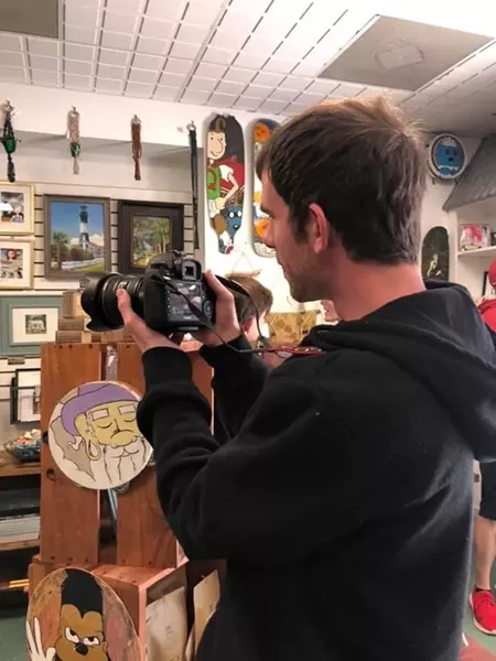 Josh Stewart, a Washed Ashore member, helps out by photographing the items for sale.