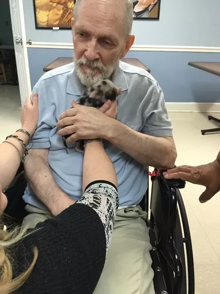 Magnolia Manor resident William Schroder enjoys cuddle therapy with Maggie. - PHOTO BY MYRA BRASWELL
