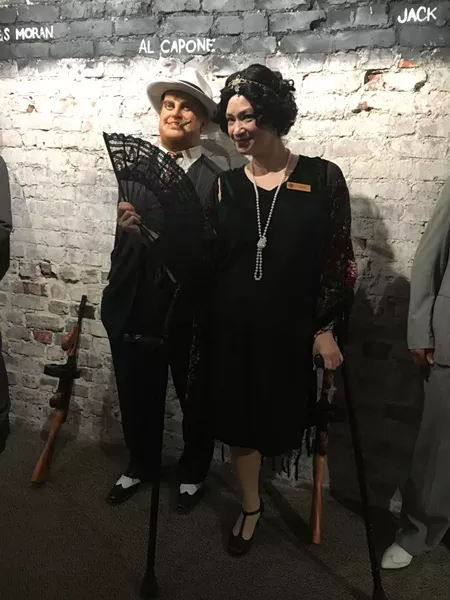 Capone’s legend is recounted by beloved theater pro JinHi Soucy Rand, who emulates the Roaring 20s in a drop-waisted dress and feather headpiece.
