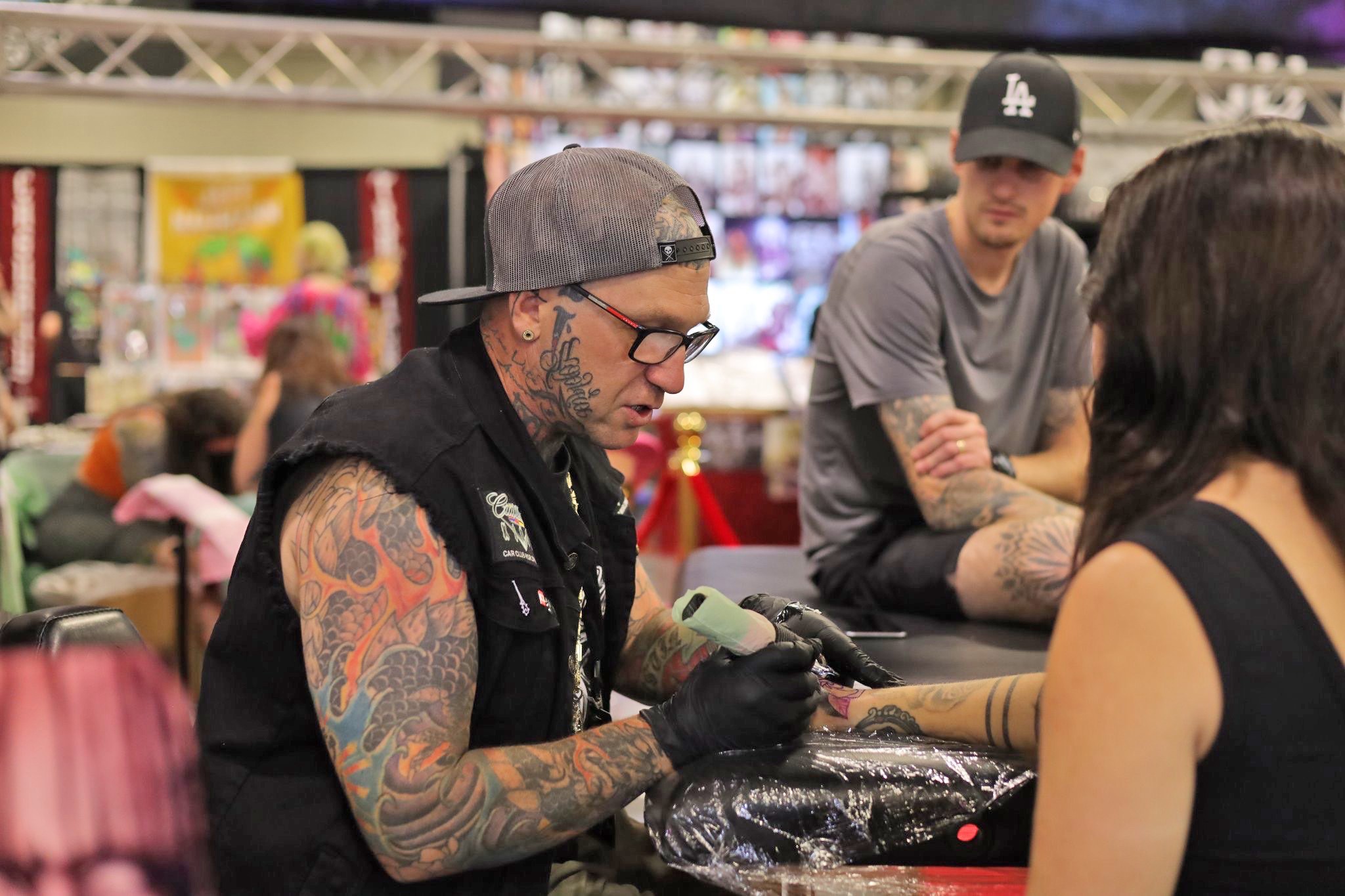 From left Lee Dreifort of Willowghby Ohio Larry Harp of Vancouver  Wash and Kai Kristensen of San Diego sit in the crowd displaying their  tattoos during the National Tattoo Convention in St