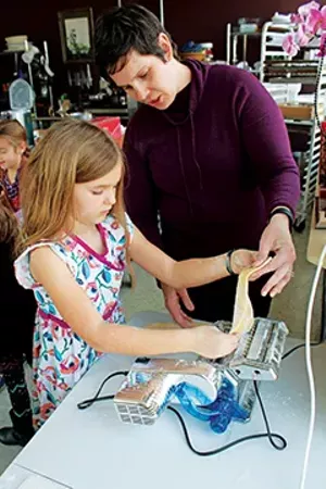 At her birthday party at Copper Pot Cooking Studio, Anna Liberman works with Denise Perry to use a pasta machine to make fettuccine noodles.
