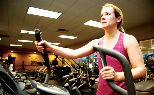 Lindsay Buckles, spinning instructor at Gold’s Gym, takes a break from riding in place to walking in place on an elliptical machine. - PHOTO BY PATRICK YEAGLE
