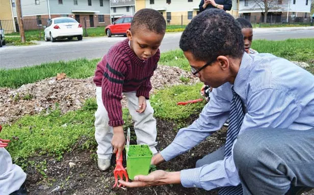 Julius Simmons, executive director of the Springfield Community Federation, helps Kamari Morgan, five, of Springfield, plant strawberries in a community garden near the Springfield Housing Authority. - PHOTO BY JACQUELINE MUHAMMAD