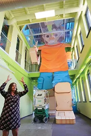 Board president Rachael Thomson is demonstrating how large Active Alex is. Active Alex is a three-story, 40-foot-tall child that you children climb in, through and around to learn about all of the body's systems. - PHOTO BY LEE MILNER