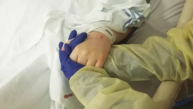 Kelli Andrews clutches her daughter’s limp hand at the St. John’s Hospital intensive care unit. - PHOTO BY BRUCE RUSHTON