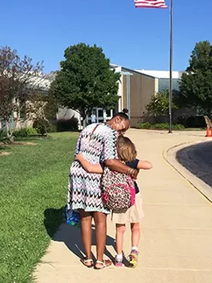 Yolanda Harrington walks one of her students into Barkstall Elementary in Champaign. Harrington, who had dreams of becoming a teacher, makes $18 an hour and works a second job. She has been a paraprofessional for 19 years. - COURTESY OF THE STUDENT’S FAMILY