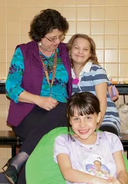 Third-graders Stephanie Conway and Amy Thomas, front, enjoy reading to Karen Osburn, a retired teacher who volunteers her time to help run McClernand's weekly Wednesday Literacy Lounge, where students can spend part of their lunch periods reading. - PHOTO BY RACHEL WELLS