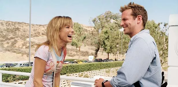 TV news reporter Hartman (Thomas Haden Church, left) feigns surprise when Mary (Sandra Bullock) once again surprises Steve (Bradley Cooper) with more crazy declarations of love