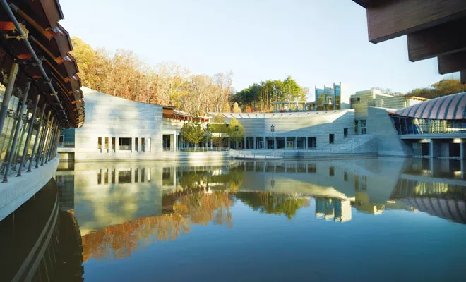 The Crystal Bridges Museum of American Art, designed by architect Moshe Safdie, is a series of pavilions nesttled in a pond.