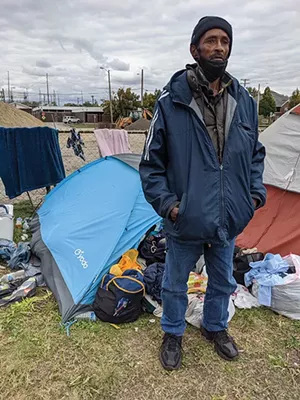 Markey Surratt outside his tent stuffed with clothes, which he says he will give to the needy. - PHOTOS BY BRUCE RUSHTON