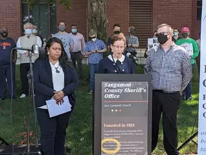 Flanked by Vanessa Knox of the Faith Coalition For The Common Good and Nick Dodson of the Sierra Club and Sangamon County Democratic Socialists of America, Susan Allen, a member of the Faith Coalition, tells the press that the sheriff's office shouldn't get an armored vehicle. - PHOTO BY BRUCE RUSHTON