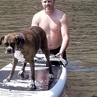 Bryan Witt helps his dog, Mocha, as she learns how to paddle board this summer.