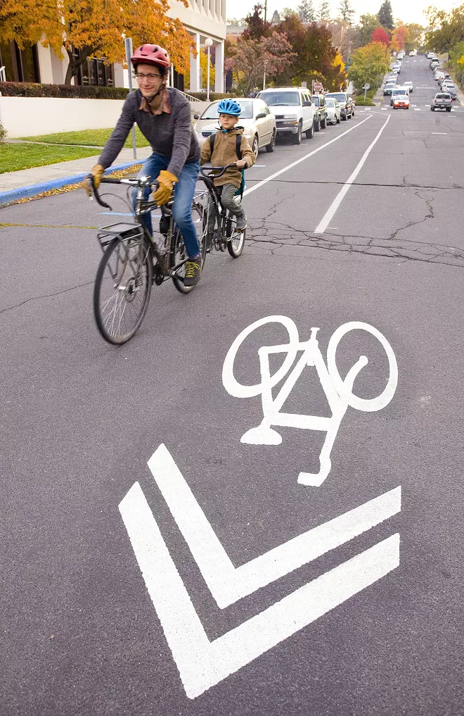 Colin Priebe rides in a bicycle lane on East Fifth Street while taking his son, Colin Priebe, to school on Thursday in Moscow. - GEOFF CRIMMINS