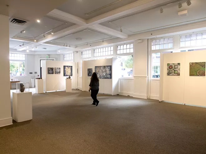 A woman walks through a vast collection of a variety of work created by local artist John Patterson at the Lewis-Clark State College Center for Arts & History on Tuesday. - TRIBUNE/PETE CASTER