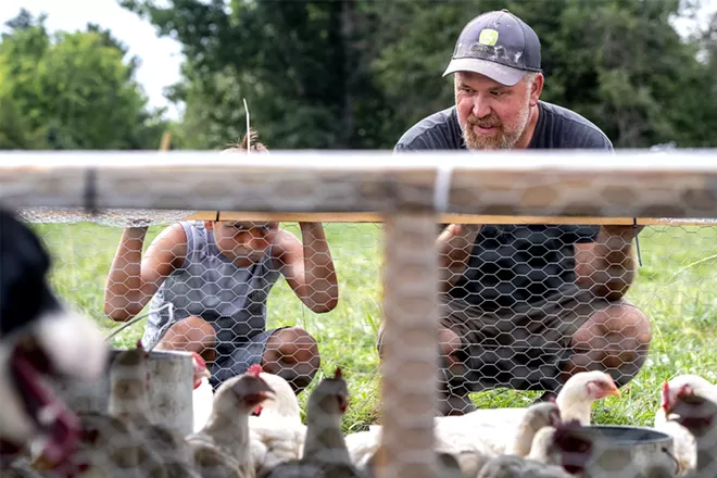 Wes Barnes and his son Jarrett Barnes, 8, look into their movable chicken coop as their herding dog Waitress (left) keeps a close eye on the chickens at the Barnes' home and farm property off Powers Avenue in Lewiston on Saturday. August Frank/Tribune - AUGUST FRANK/TRIBUNE
