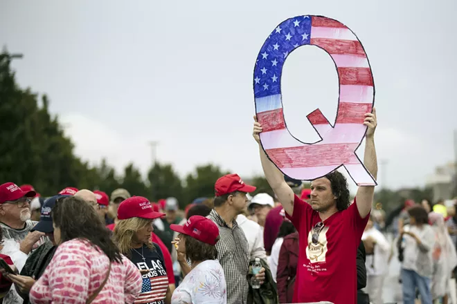 In this Aug. 2, 2018, file photo, David Reinert holding a Q sign waits in line with others to enter a campaign rally with President Donald Trump in Wilkes-Barre, Pa. A far-right conspiracy theory formed online has crept into the mainstream political arena. It's called QAnon, and it centers on the baseless belief that President Donald Trump is waging a secret campaign against enemies in the “deep state.” - AP PHOTO/MATT ROURKE