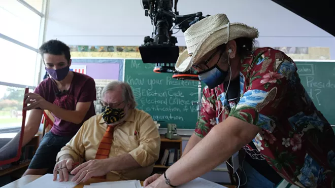 Director Rantz Hoseley discusses the action and camera angles with actor Patrick Broemeling while Vin Carlston, key grip, adjusts the glare coming off - the pages. - DAN BLAKNEY