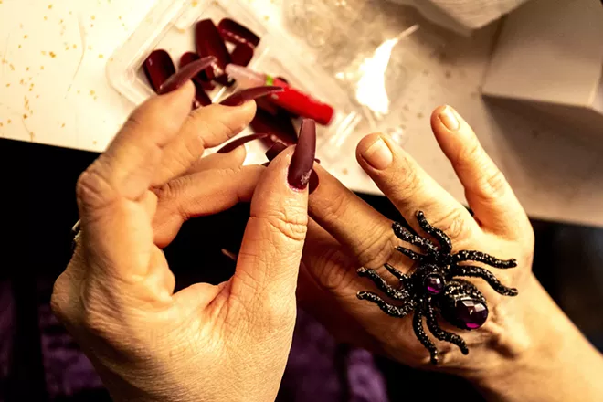 Amy Stout, playing Morticia Addams, puts long nails on before a rehearsal for the Addams Family at the old Lewiston High School on Monday evening. - AUGUST FRANK/360