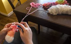 Mosman’s current project, a rainbow alpaca, is worked on in this photo. One of the alpaca’s legs is worked on by holding a skein of white yarn double with another skein of rainbow-colored yarn. - CAITLIN BEESLEY/TRIBUNE