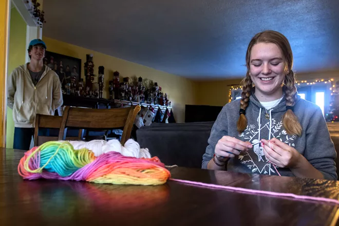 Penelope “PJ” Mosman laughs at a joke her brother, William Mosman, just told as she crochets at the family dinner table in Clarkston. Mosman, 17, learned how to crochet as a child but took up the hobby in earnest during the pandemic and has been selling her creations at fiber festivals and on the website Etsy for the past year. - CAITLIN BEESLEY/TRIBUNE