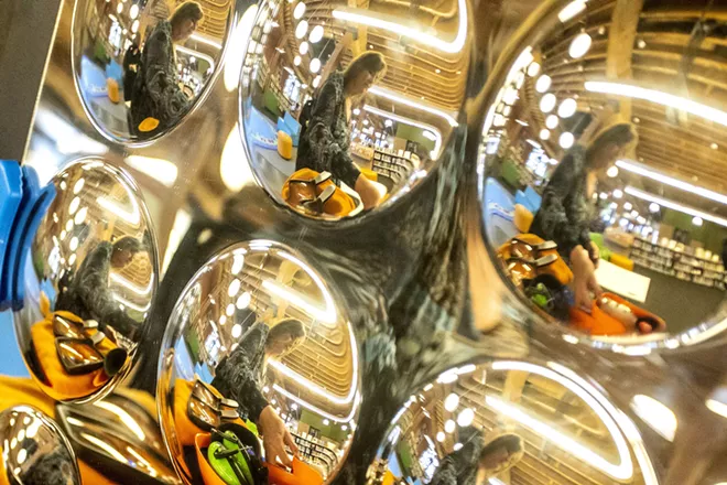 Colleen Olive, Lewiston City Library youth services librarian, is reflected in a bubble mirror as she reaches for a sensory kit last at the library.