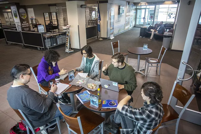 Ash Demattos makes a move in a game of jumbo Connect 4 while waiting for others to arrive for an LGBTQ+ support group meeting Saturday at the Shooting Star Cafe in the Lewiston airport.