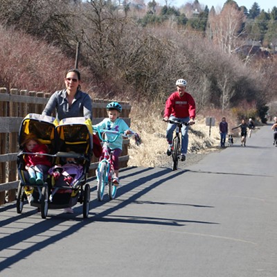 A woman jogs pushing a two seat stroller with the rest of her family in tow riding bikes on the Bill Chipman Palouse Trail just outside Pullman on Saturday, March 21, 2020.  People were enjoying the outdoors and taking temporary respite from their concerns over the Covid-19 pandemic.  Photo taken by Keith Collins.