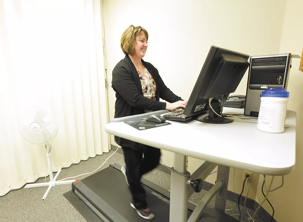 Administrative assistant Kris Stensatter strolls while she types at the Spokane Regional Health District's treadmill workstation. - YOUNG KWAK