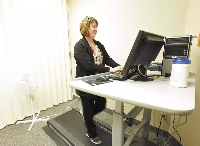 Administrative assistant Kris Stensatter strolls while she types at the Spokane Regional Health District's treadmill workstation. - YOUNG KWAK