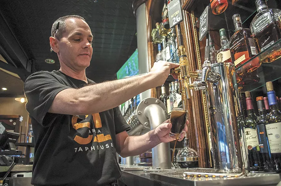 Area 51 Taphouse product manager Bill Matthew pours a stout from River City Brewing. - SARAH WURTZ