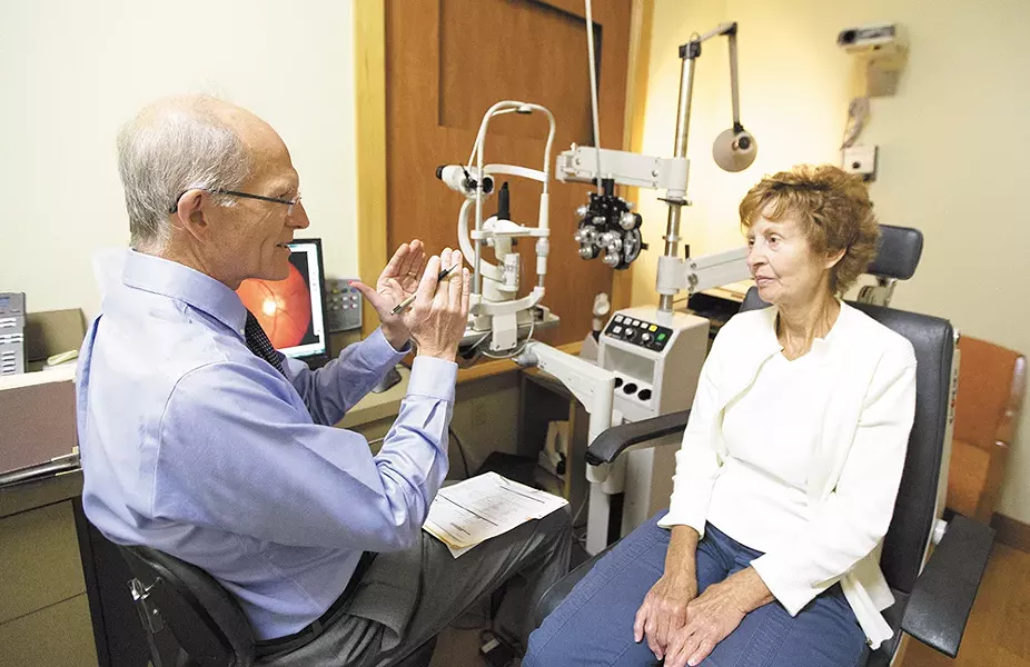 Arlene Bennett listens as Optometrist Todd Wylie explains the results of her eye exam. - YOUNG KWAK