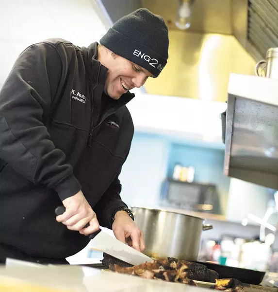 Driver and paramedic Kasey Austin slices meat for sandwiches at Spokane Fire Station No. 2. - YOUNG KWAK