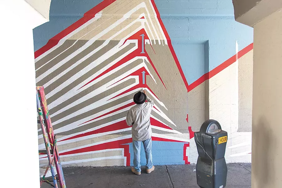 Jesse Santos helps paint the Wall Street mural. - MATT WEIGAND