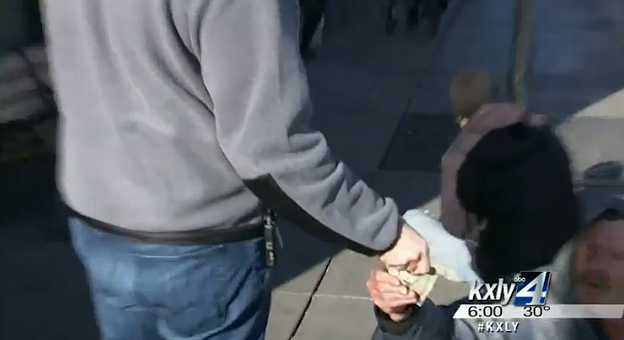 John Doe gives a stack of cash to a man on the sidewalk. - KXLY