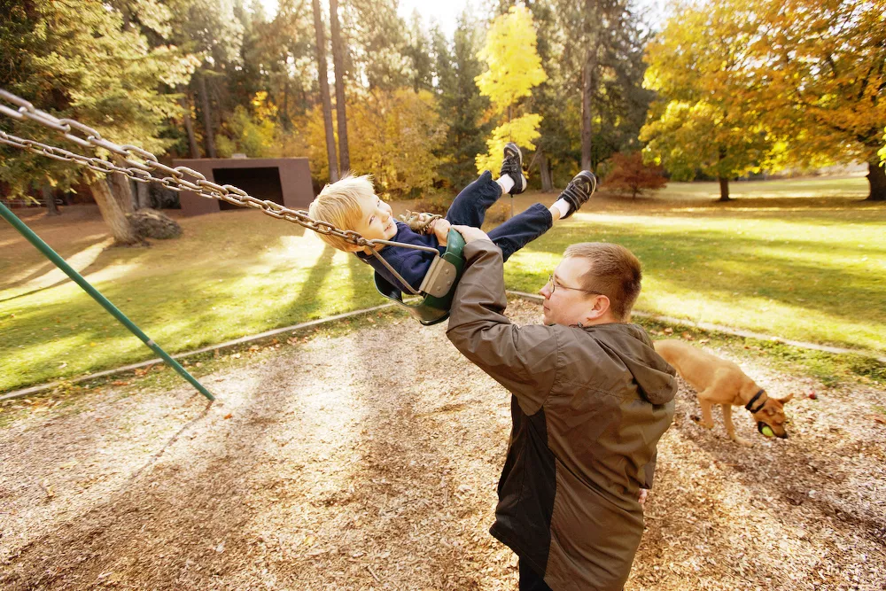 Justin Tolleson pushes his 2 year old son Derek on a swing as their 1 year old Rhodesian Ridgeback mix Tank plays nearby at Lincoln Park. - YOUNG KWAK