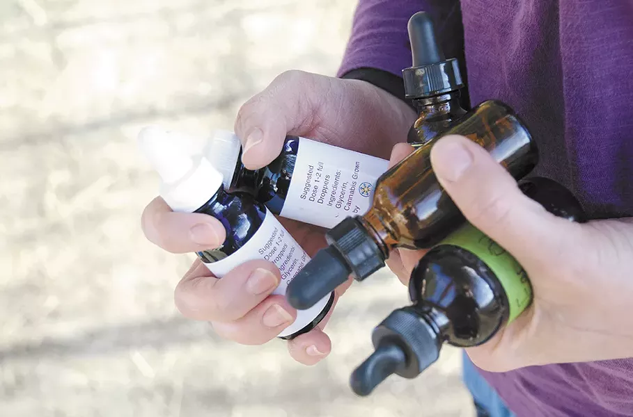 Kim Kalua juggles several tincture bottles for high-cannabidiol marijuana extract oil that the family has used to treat Koa's epilepsy. - JACOB JONES